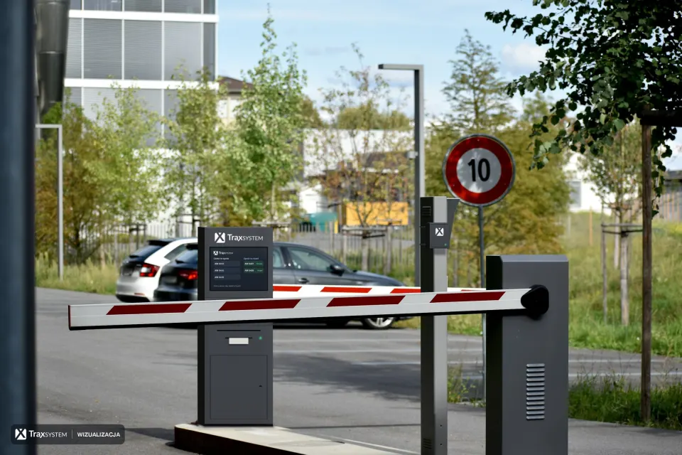 Szlaban z biało-czerwonym ramieniem przy wjeździe na parking. Za ramieniem, na wysepce, naniesiono kiosk kierowcy z logo TraxSystem, ekranem kolejki i przepustką, a na słupku obok urządzenie brzegowe ANPR.