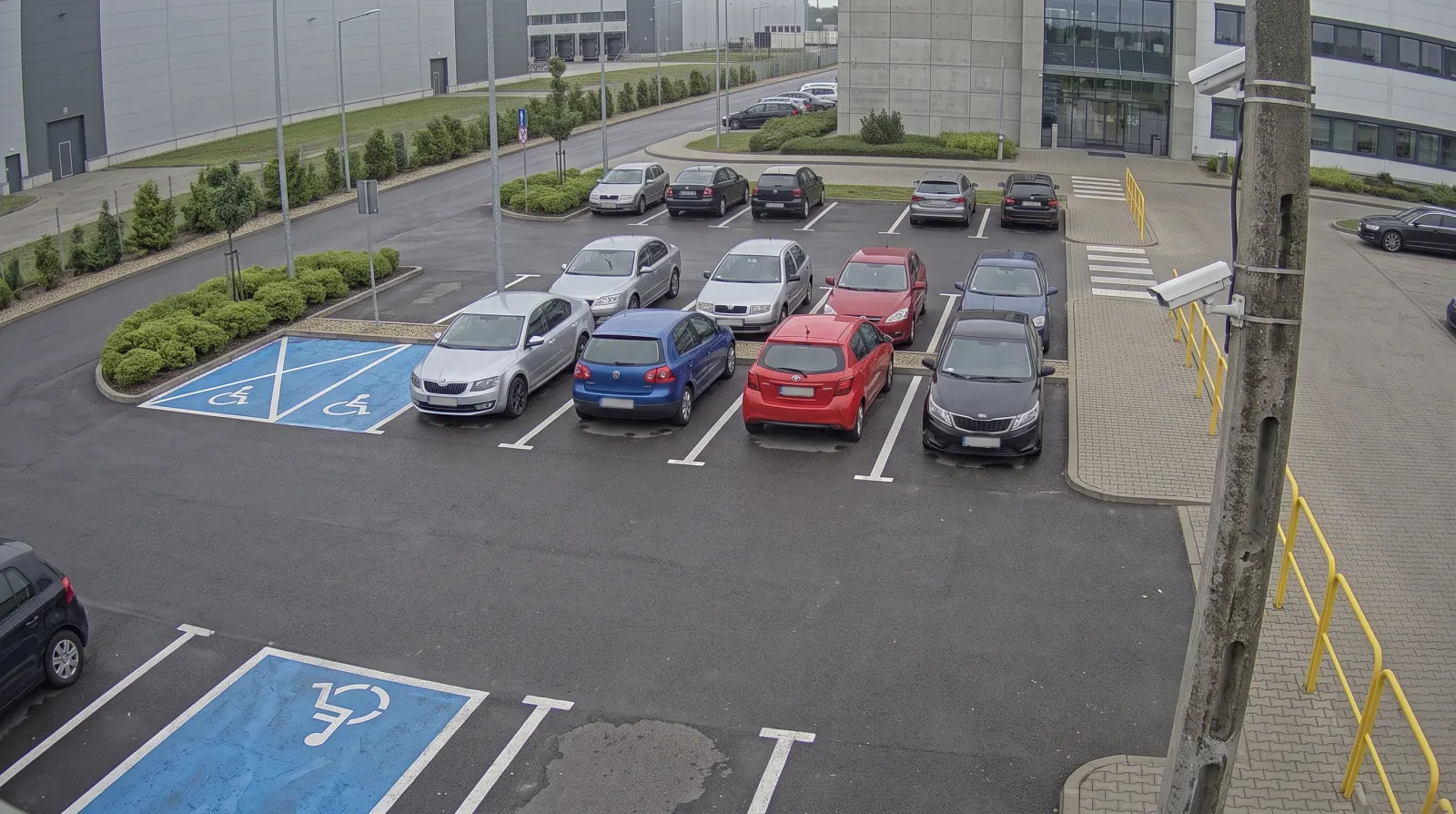 Illustrative camera frame above a car park in front of an office and warehouse building. Overlaid are the numbered points and a card showing how much of the tenant’s allocation of spaces is taken.