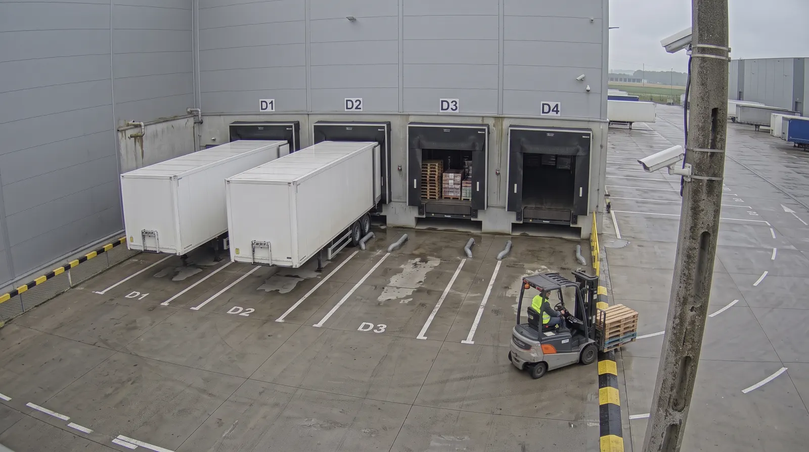 Illustrative camera frame above docks D1–D4: two trailers backed onto the docks, open dock doors with pallets and a forklift. Overlaid are the numbered points and a card with the dispatcher’s day plan.